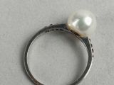 silver ring with white pearl on top of it on a white surface