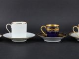 four cups and saucers are lined up on a black surface