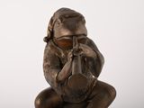 a bronze figurine of a woman sitting on a rock