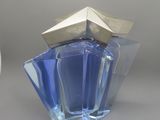 une bouteille en verre bleue avec un bouchon argenté, posée sur une table