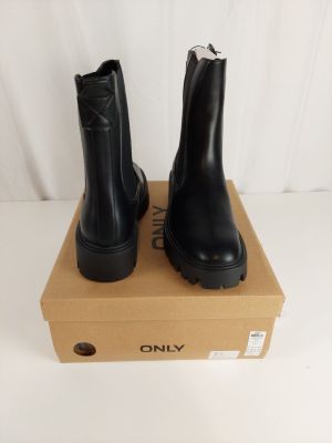 les bottes noires sont posées sur une boîte en carton, elle-même posée sur une surface blanche