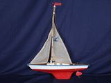 maquette d'un voilier posée sur un socle, sur fond bleu