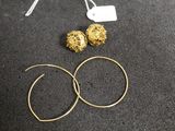 a close up of a pair of gold hoop earrings on a black surface