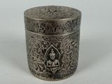 an old silver box with a buddha on it on a white surface