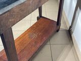 a wooden table with a black marble top on a tiled floor