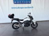 une photo d'une moto garée devant un panneau annonçant une vente aux enchères