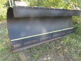 a close up of a large black snow plow sitting in the grass