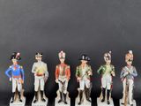 five figurines of men in uniforms and hats are lined up in a row