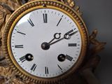 a gold clock with roman numerals on the face