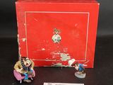 une boîte rouge sur laquelle sont posées deux figurines représentant des personnes assises
