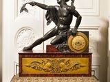 une statue d'un homme tenant une horloge au-dessus d'une table