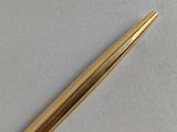 a close up of a gold colored pen on a white surface