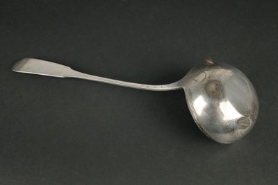 une cuillère en argent dont le manche repose sur une surface noire