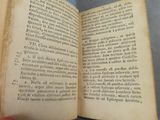 someone is holding an open book in their hand on a table