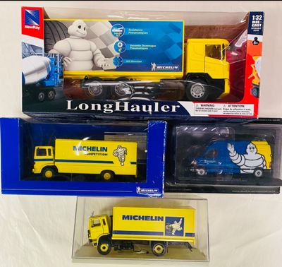 Trois camions miniatures sont exposés dans une vitrine posée sur une surface blanche.