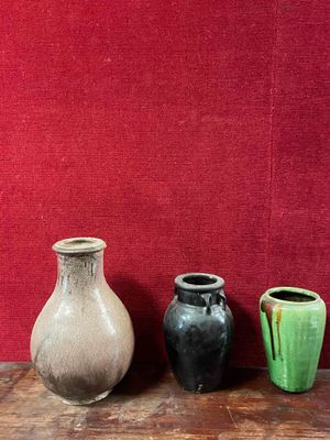 three vases sitting on a table in front of a red wall