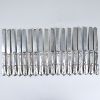 huit couteaux d'argenterie sur une table blanche