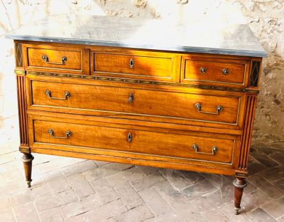 a wooden dresser with marble top on a brick floor