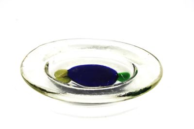 une pilule bleue et verte dans un bol en verre posé sur une surface blanche