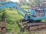 une petite pelleteuse bleue qui est garée dans l'herbe