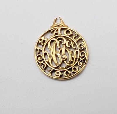 a gold plated pendant with a monogram in the center