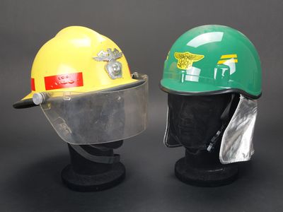 une paire de casques de chantier jaunes et verts exposés sur fond noir