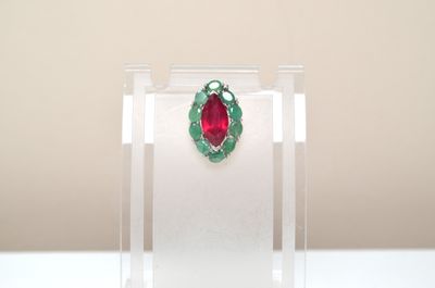 ruby and emerald leaf broochle on display in clear acrylic case