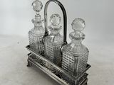 a silver plated glass decanter with three bottles on a stand