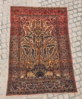 un vieux tapis posé à même le sol, sur lequel est représenté un arbre de vie
