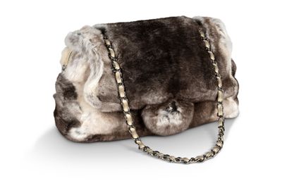 sac à main en fourrure marron et blanche avec une bandoulière en chaîne, sur fond blanc