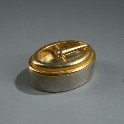 a silver and gold container with a handle on a table