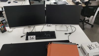 deux écrans d'ordinateur et un clavier posés sur le bureau