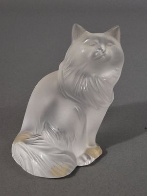 une figurine de chat blanc posée sur une surface grise