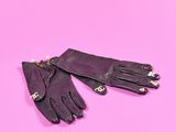deux gants en cuir noir ornés de perles, sur fond rose