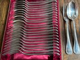 silverware in a velvet case on a wooden table with a spoon and fork