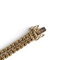 a close up of a gold chain bracelet on a white surface