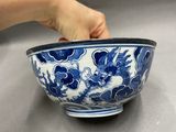 someone holding a blue and white bowl with flowers in it