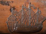 a wooden box with a metal ship on it