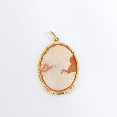 a close up of a gold plated pendant with a woman ' s profile