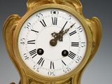 a gold clock with roman numerals on the face