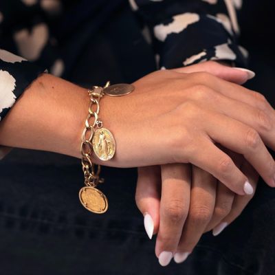 main de femme portant un bracelet en or et un bracelet composé de pièces d'or