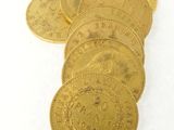 plusieurs pièces d'or posées sur une surface blanche, sur fond blanc