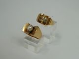 pair of gold and pearl earrings on clear acrylic stand