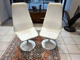 deux chaises blanches posées sur un tapis dans un salon