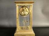 a gold clock on a black table with a white background