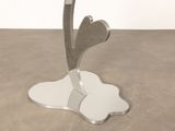 a metal table with a glass top and a flower on it