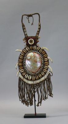 an image of a necklace with shells and beads on a stand