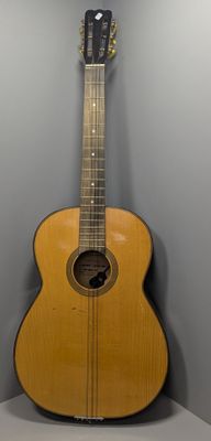 une guitare acoustique posée sur un support dans un coin