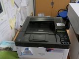 a printer sitting on top of a desk next to a stack of papers