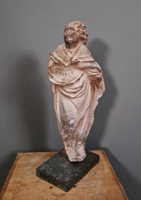 statue d'un homme tenant un livre posé sur une table en bois